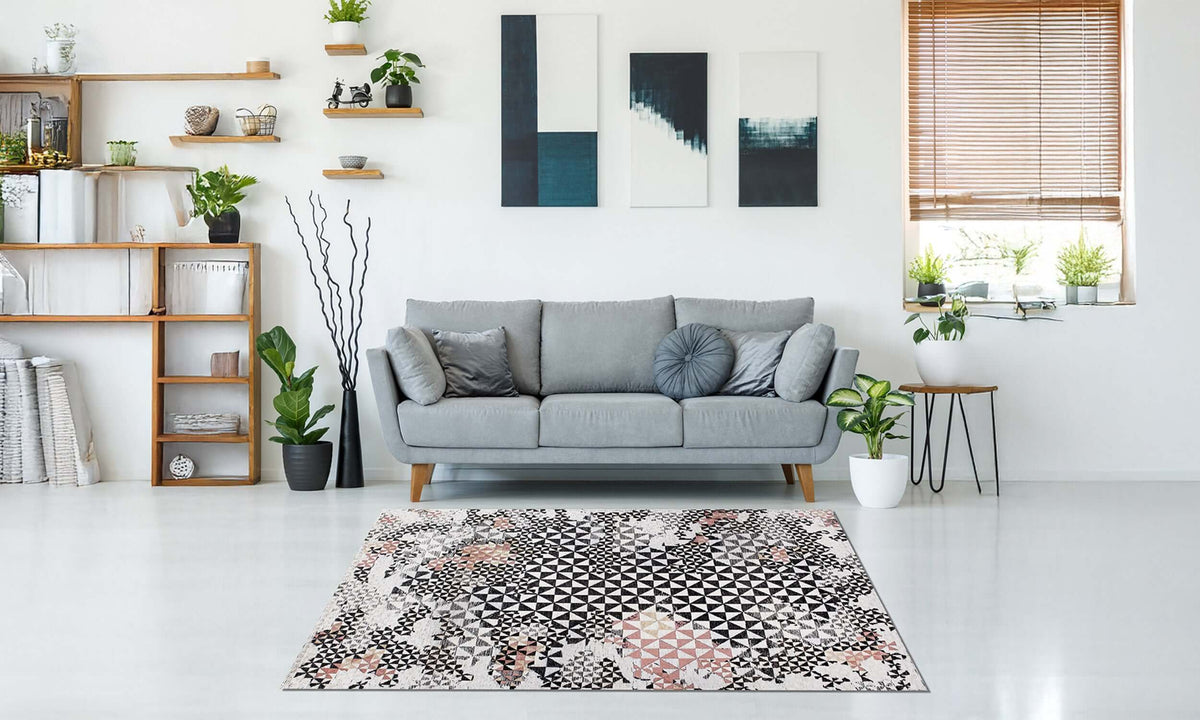 Moderner Teppich in einem stilvollen Wohnzimmer mit grauem Sofa und dekorativen Pflanzen, der lebendige Muster und Texturen zeigt.