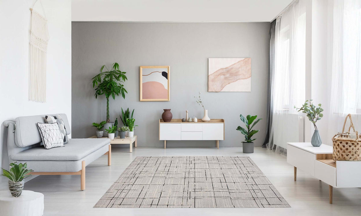 Spacious modern living room with a warm gray rug, plants, and stylish furniture accents.