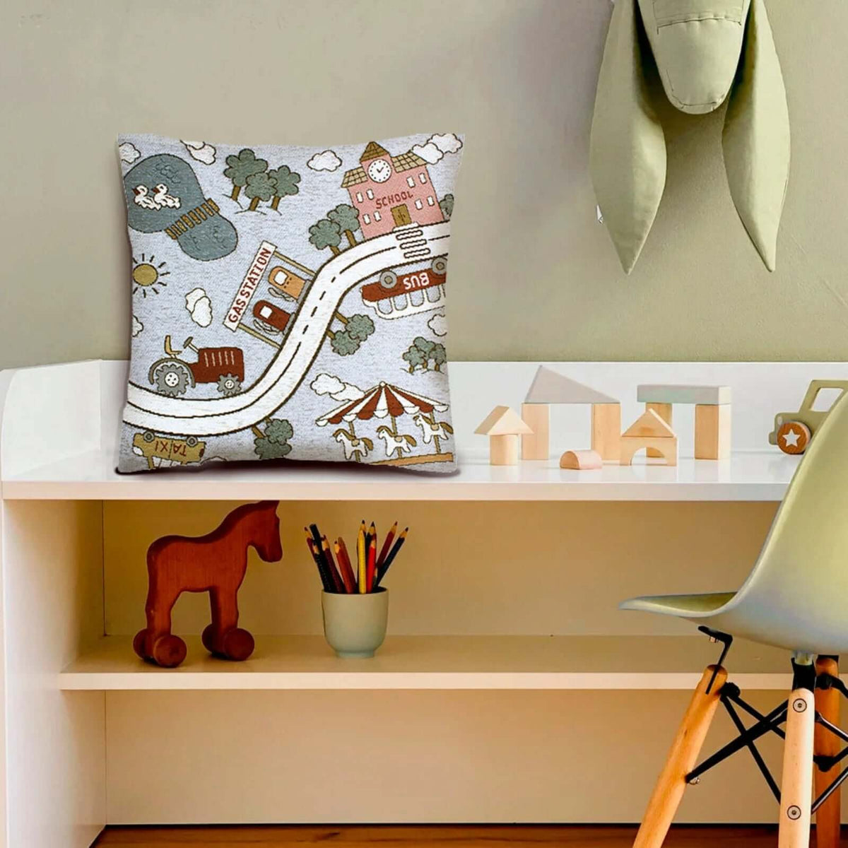 COPPIA CUSCINI ARREDO JACQUARD SFODERABILI PISTA su un tavolo con giocattoli e decorazioni per la casa.