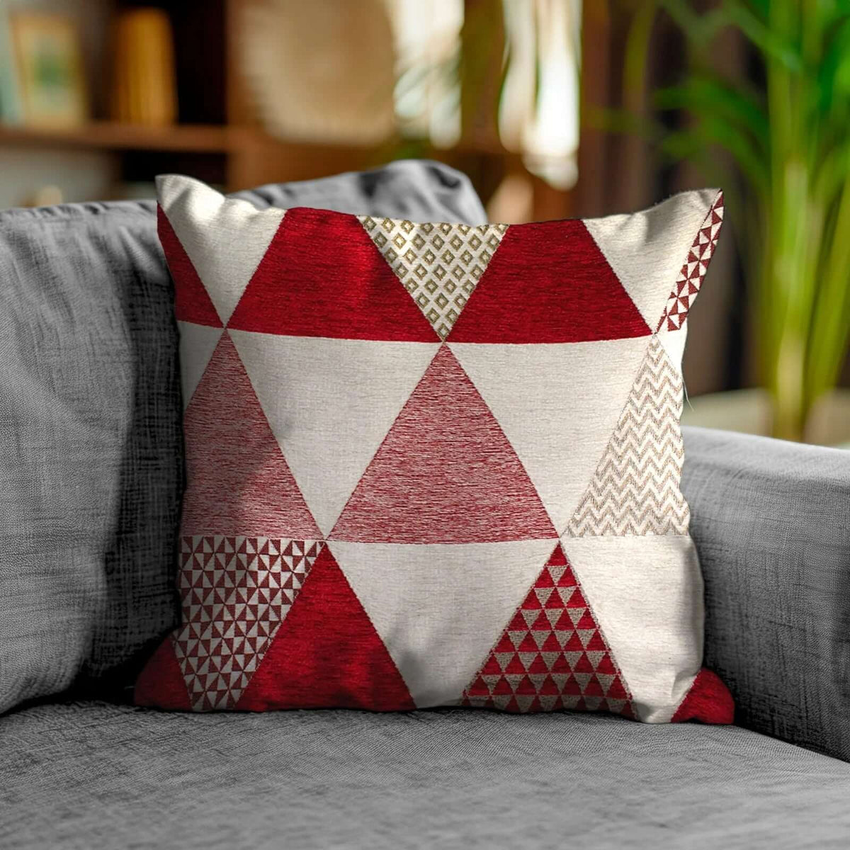 COPPIA CUSCINI ARREDO JACQUARD SFODERABILI TRIANGOLI su un divano in tessuto grigio.