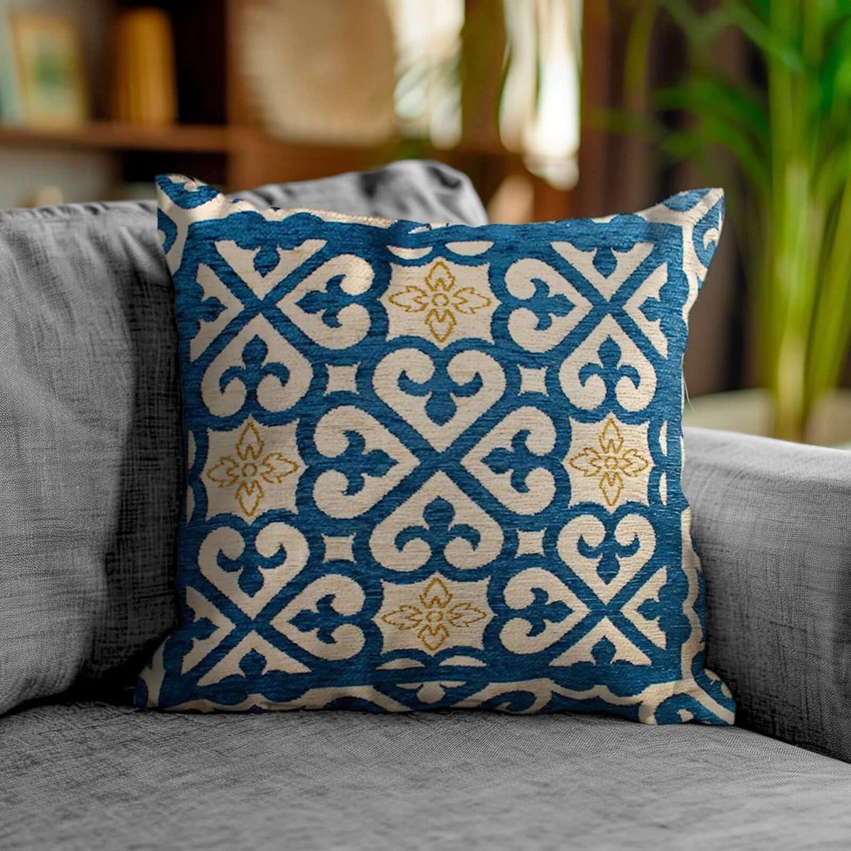 COPPIA CUSCINI ARREDO JACQUARD SFODERABILI ARABIC su un divano grigio, decorato con un motivo blu e dorato.