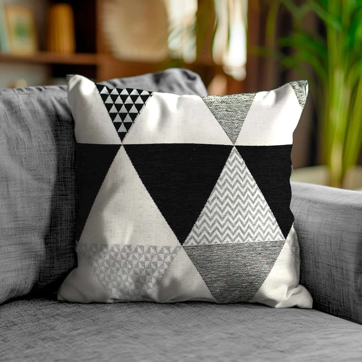 COPPIA CUSCINI ARREDO JACQUARD SFODERABILI TRIANGOLI su un divano beige, design geometrico in bianco e nero.