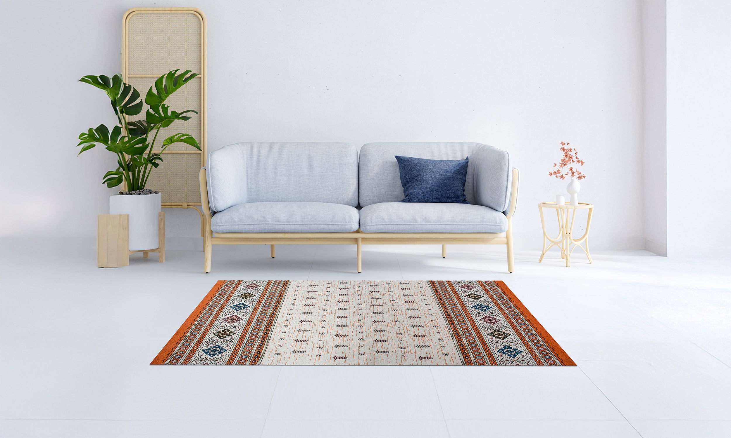 TAPPETO ARREDO LOOM RUGGINE 115x175 cm su pavimento bianco con divano moderno e pianta decorativa.