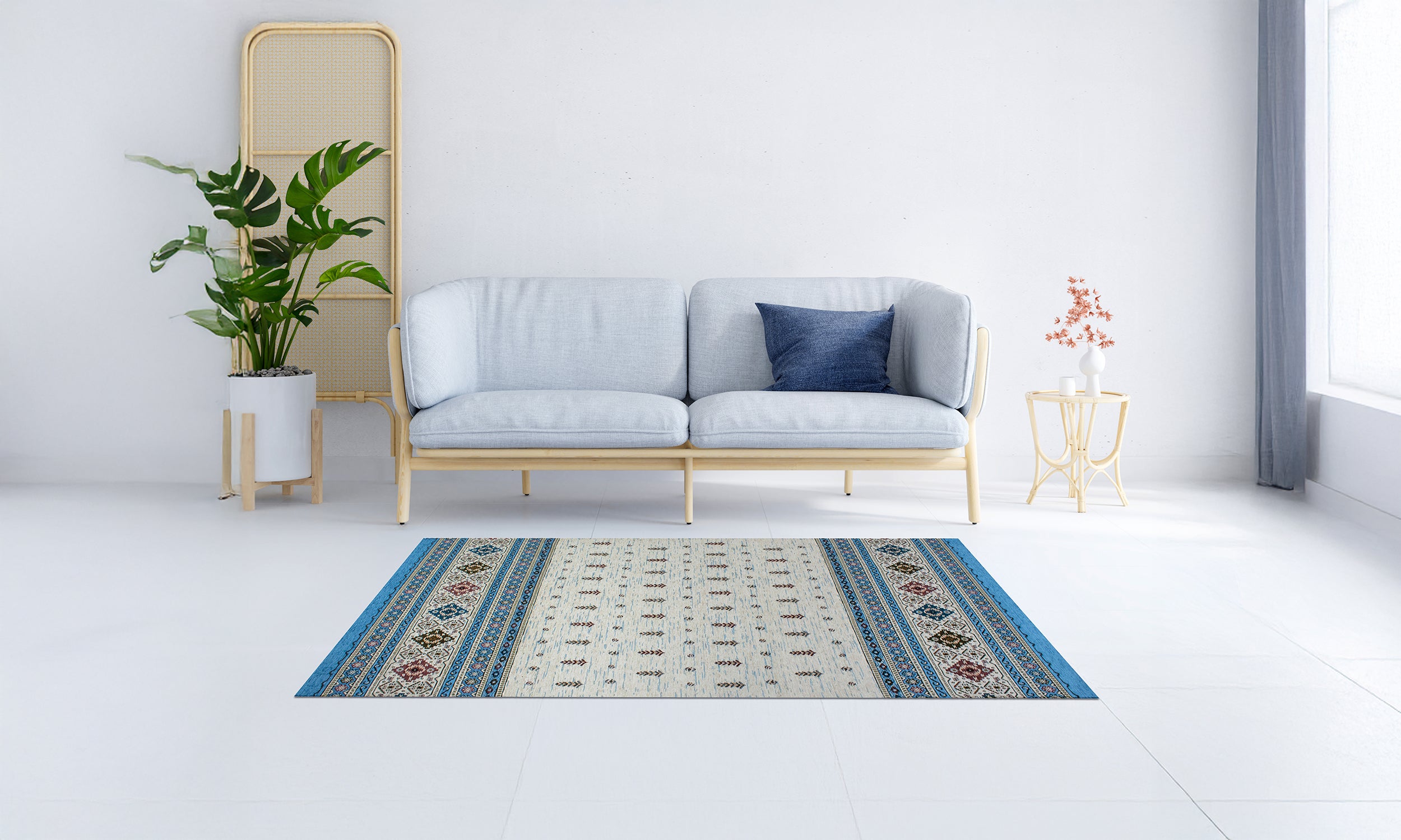 Modern light blue area rug with intricate design placed in a bright living room space with a sofa and plants.